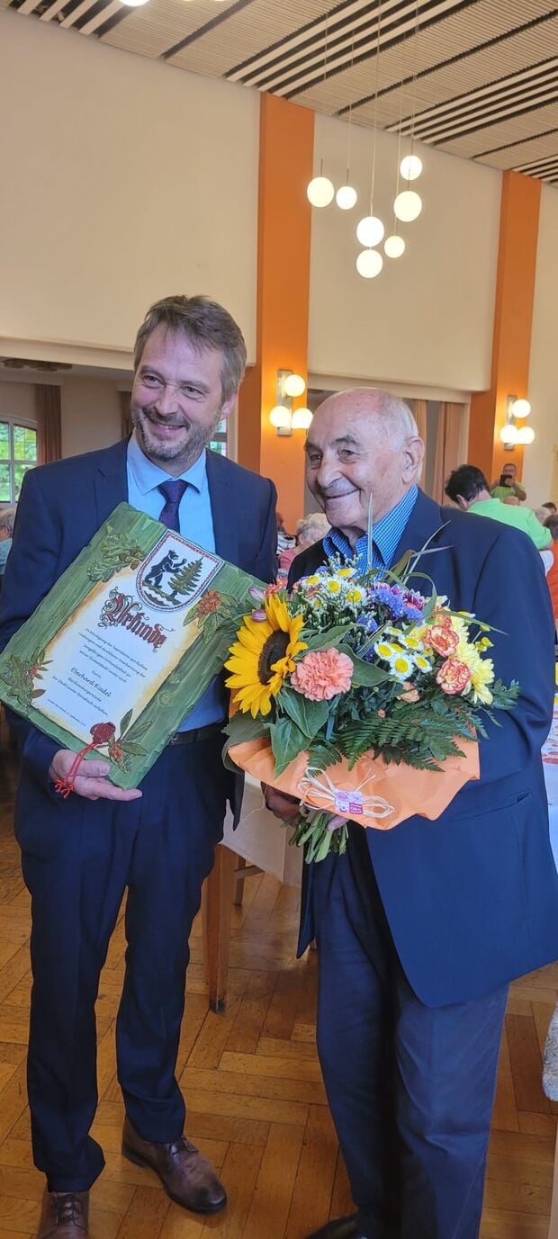 Eberhard Riedel nimmt mit Blumenstrauß die Ehrenbürgerurkunde von Lauter entgegen