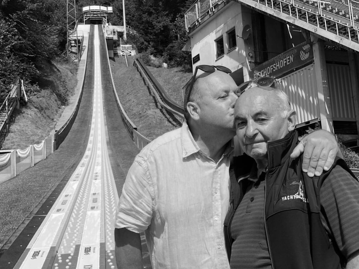 Eberhard und Peter Riedel im Arm, im Hintergrund die Anlaufspur einer Skisprungschanze