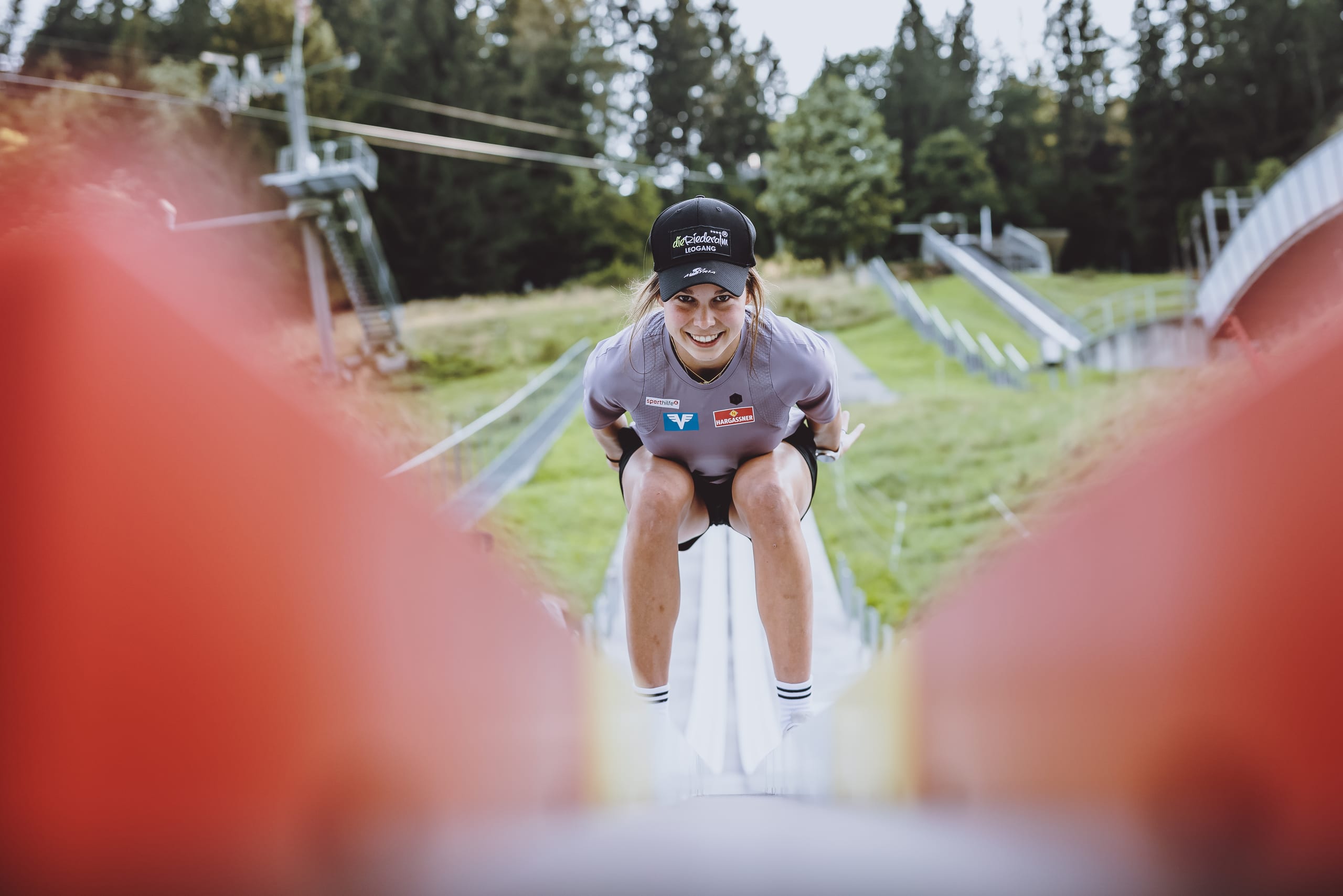 Athletin in der Anfahrtshocke auf der CLUBTRACK-Anlaufspur einer Vereinsschanze