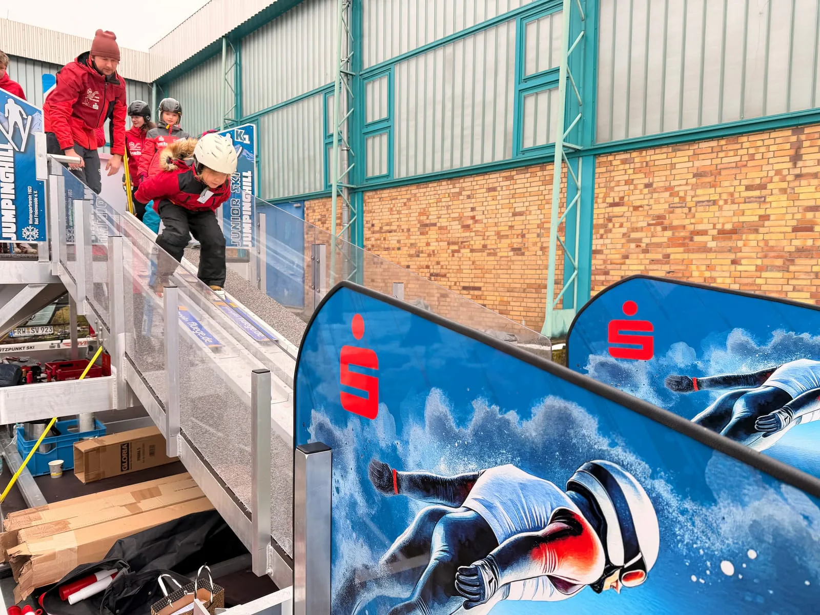 Kind mit Helm startet auf der mobilen Skisprungschanze bei einer Veranstaltung