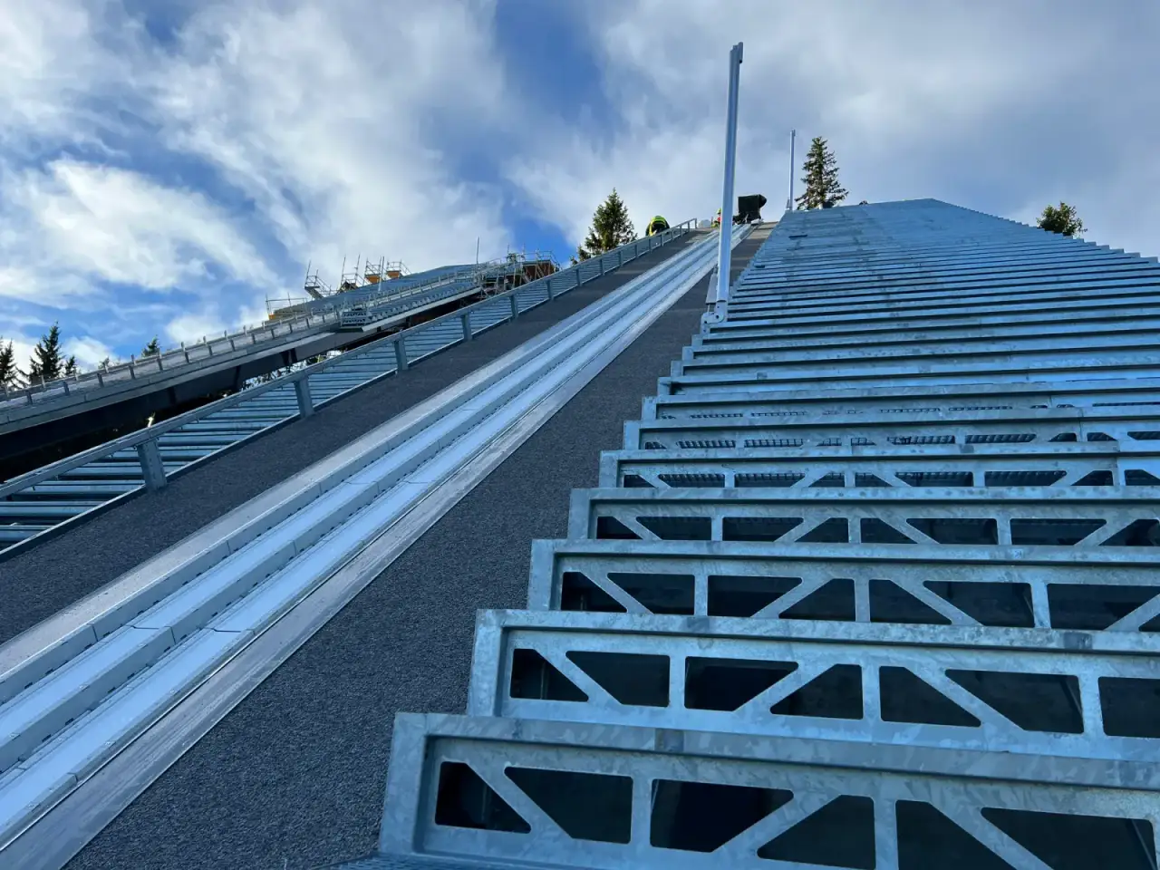 Stahltreppe und Geländer entlang der Anlaufspur einer Skisprungschanze